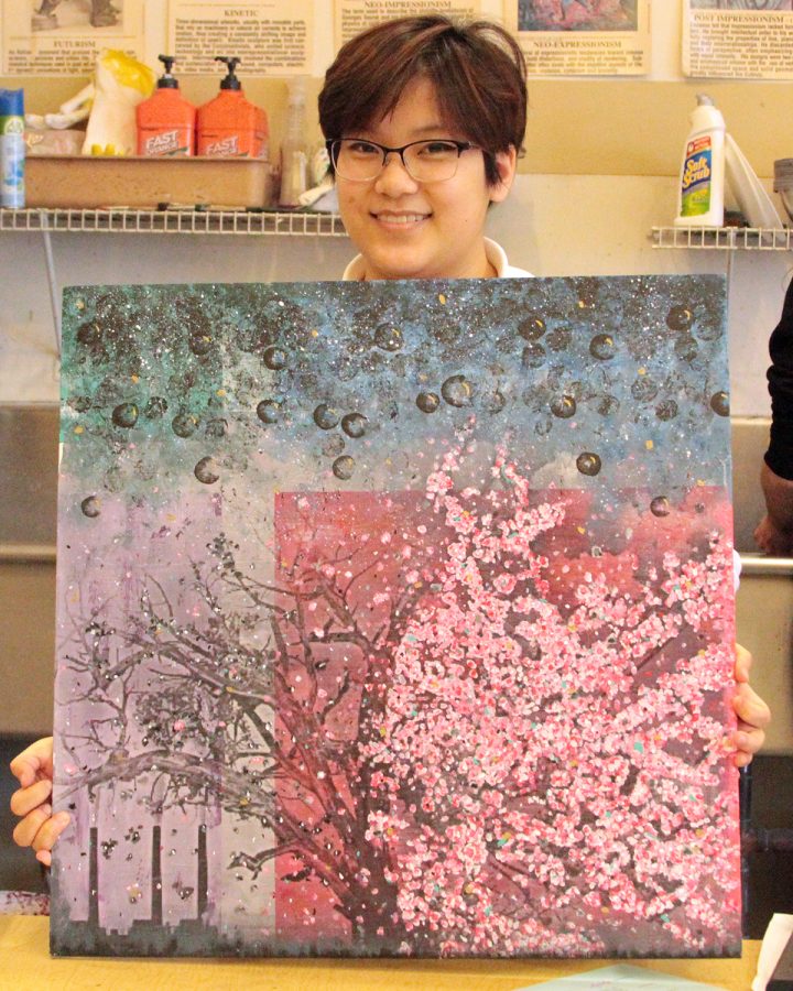 Junior Kyra Graap shows off her painting titled Corruption that she submitted to the Juried Arts Exhibition