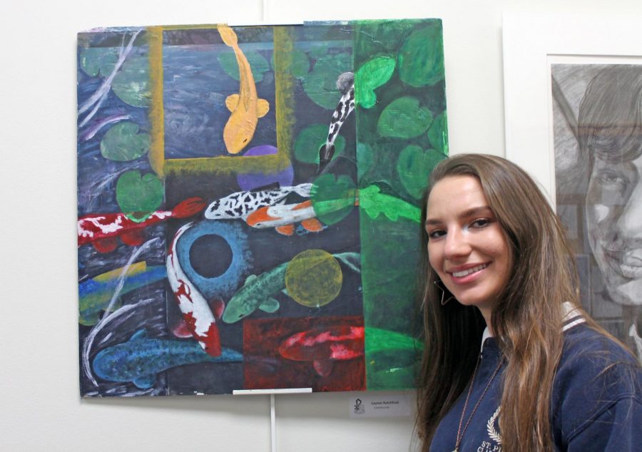 Senior Lauren Ratchford stands next to a painting titled Community that she submitted to Juried Arts Exhibition. 