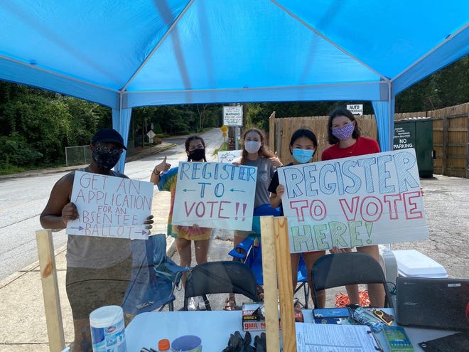 Junior Ava Nieman (2nd from right)  stands at a booth outside Oak Grove Market last fall to encourage young adults to register to vote. 