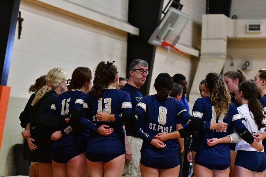 The volleyball team huddles together with head coach John Frederick during a match...