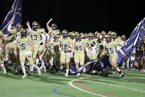 The football team crashes through the banner on Homecoming night as they prepare to battle Riverwood. The Golden Lions won the game 41-14.