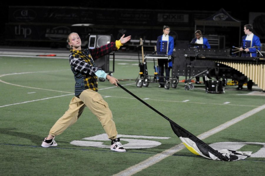 Senior Lily Perella performs with the marching band at halftime of the football game against Marist in October. Although this years colorguard only had two members (Perella and junior Berlande Strassner), they placed first at both their competitions this year.