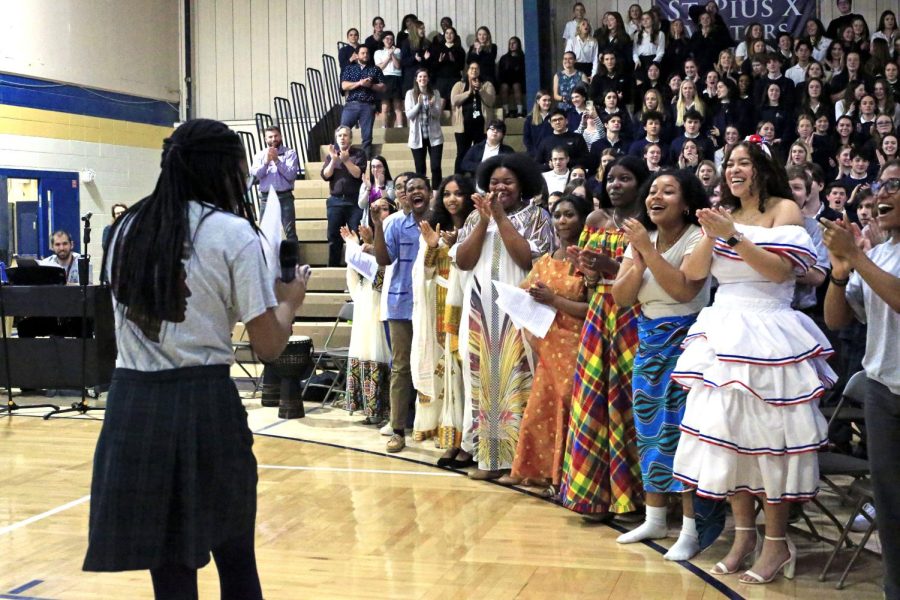Participants in the fashion show applaud senior Omeno Abutu at the end of her singing performance