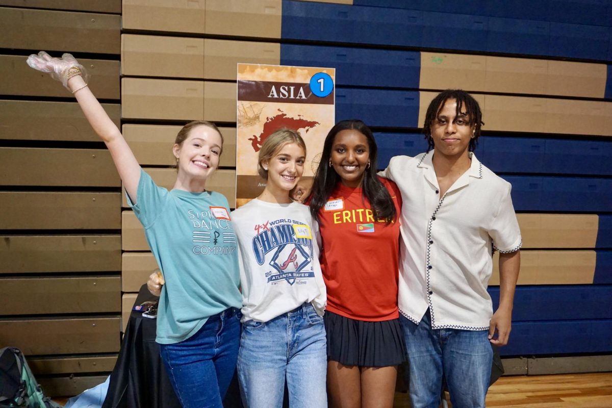 Seniors Addison McKee and Lily Tolusso, junior Soliana Araya, and senior Josh Yimtatu voluteer at Heritage Homecoming. Yimtatu and his junior brother, Zach, also participated in the international fashion show. 